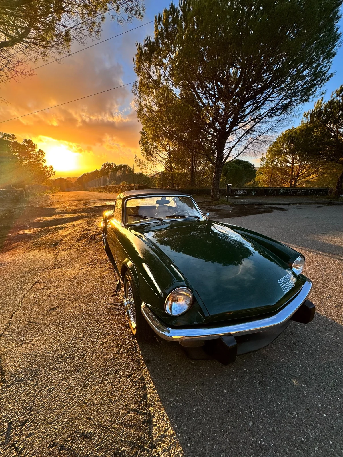 La Triumph Spitfire verde inglese illuminata dalla luce dorata del tramonto